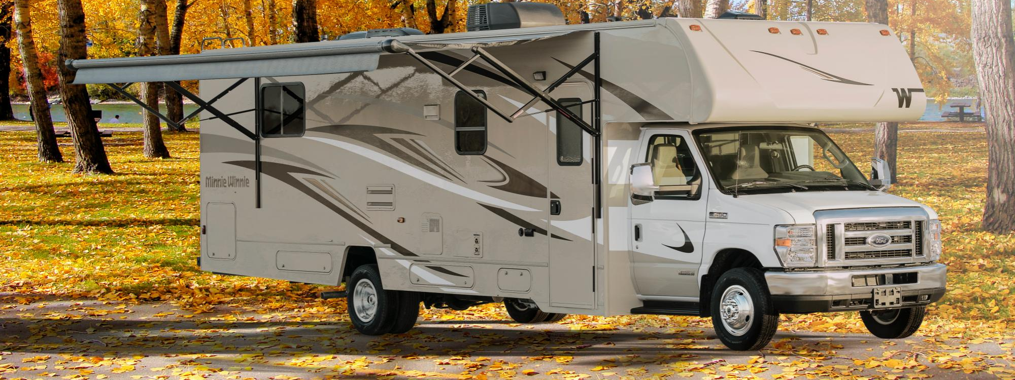 Winnebago Minnie Winnie with the awning extended with fall color trees in the background